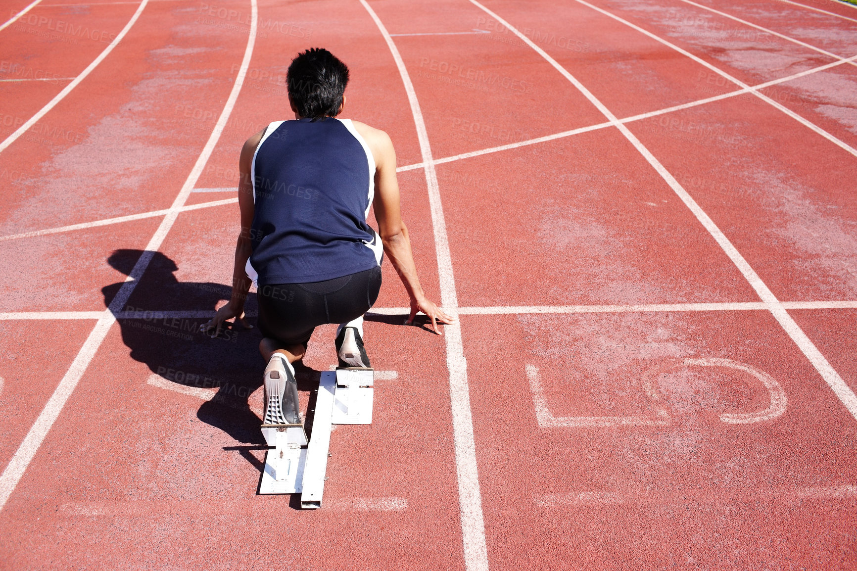 Buy stock photo Field runner, back and man at start block at track for race, sports competition and training for fitness. Arena, ready and athlete prepared for sprint, speed and fast performance outdoor at stadium