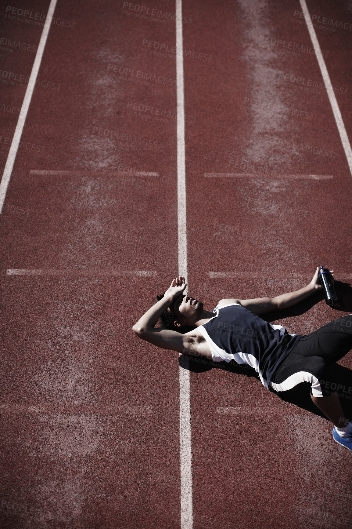 Buy stock photo A young runner lying down on the tartan track