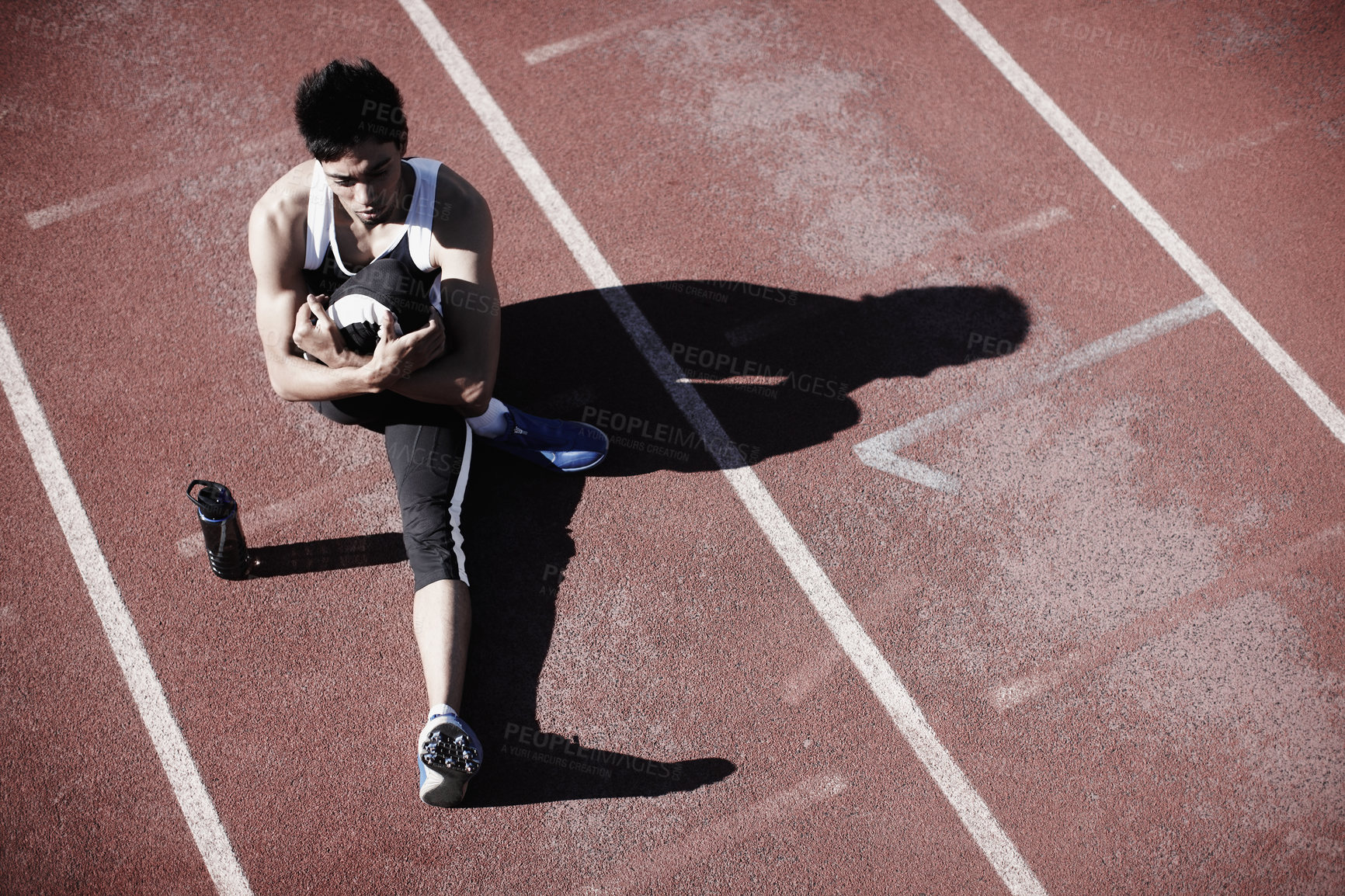 Buy stock photo Man, athlete and stretching legs on running track, warm up and preparation for exercise or workout. Male person, starting block and outdoor for fitness, water bottle and ready for marathon training