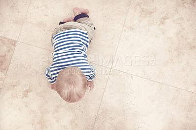 Buy stock photo High angle view of a baby boy crawling along the floor at home