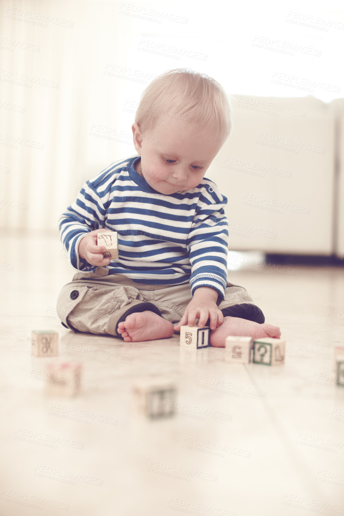 Buy stock photo A cute baby boy at home on the floor, playing with some wooden blocks