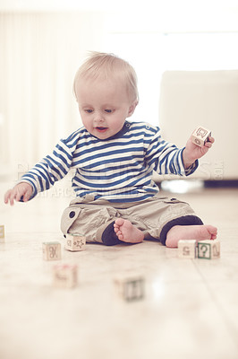 Buy stock photo A cute baby boy at home on the floor, playing with some wooden blocks