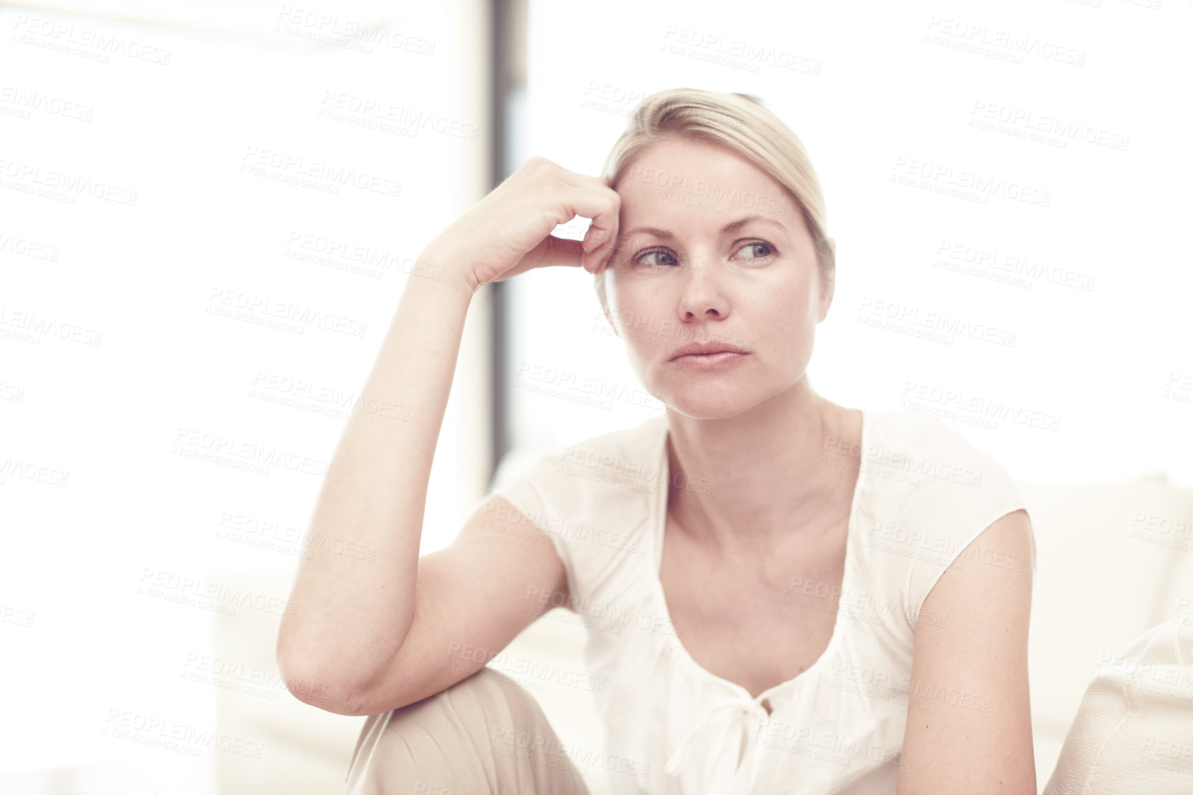 Buy stock photo A concerned looking blonde woman looking away while sitting by herself