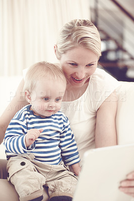 Buy stock photo An attractive young mother showing her curious baby a touchscreen tablet