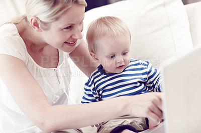 Buy stock photo An attractive young mother showing her curious baby a laptop
