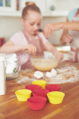 Buy stock photo Mother, girl and cups in kitchen for baking, teaching and bonding with support, bowl and ingredients. Family, kid and help in house for cooking, cupcakes and development with flour, wheat or learning