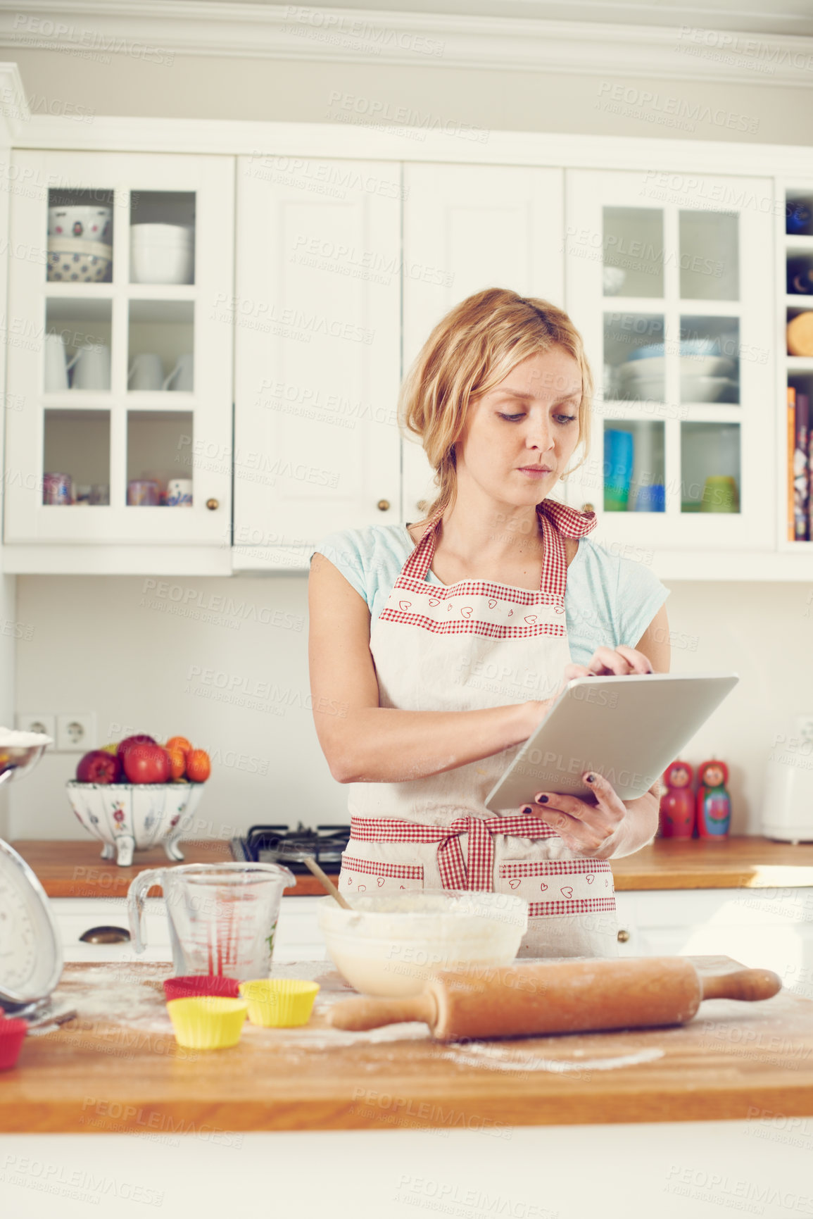 Buy stock photo Woman, tablet and online in kitchen for baking, cookies and dessert with video, bowl and streaming. Female person, tech and recipe in home for cooking, cupcakes and food with flour, wheat or research