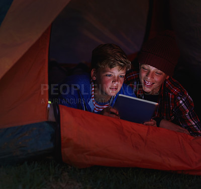 Buy stock photo Cropped shot of two young boys sharing a digital tablet while camping