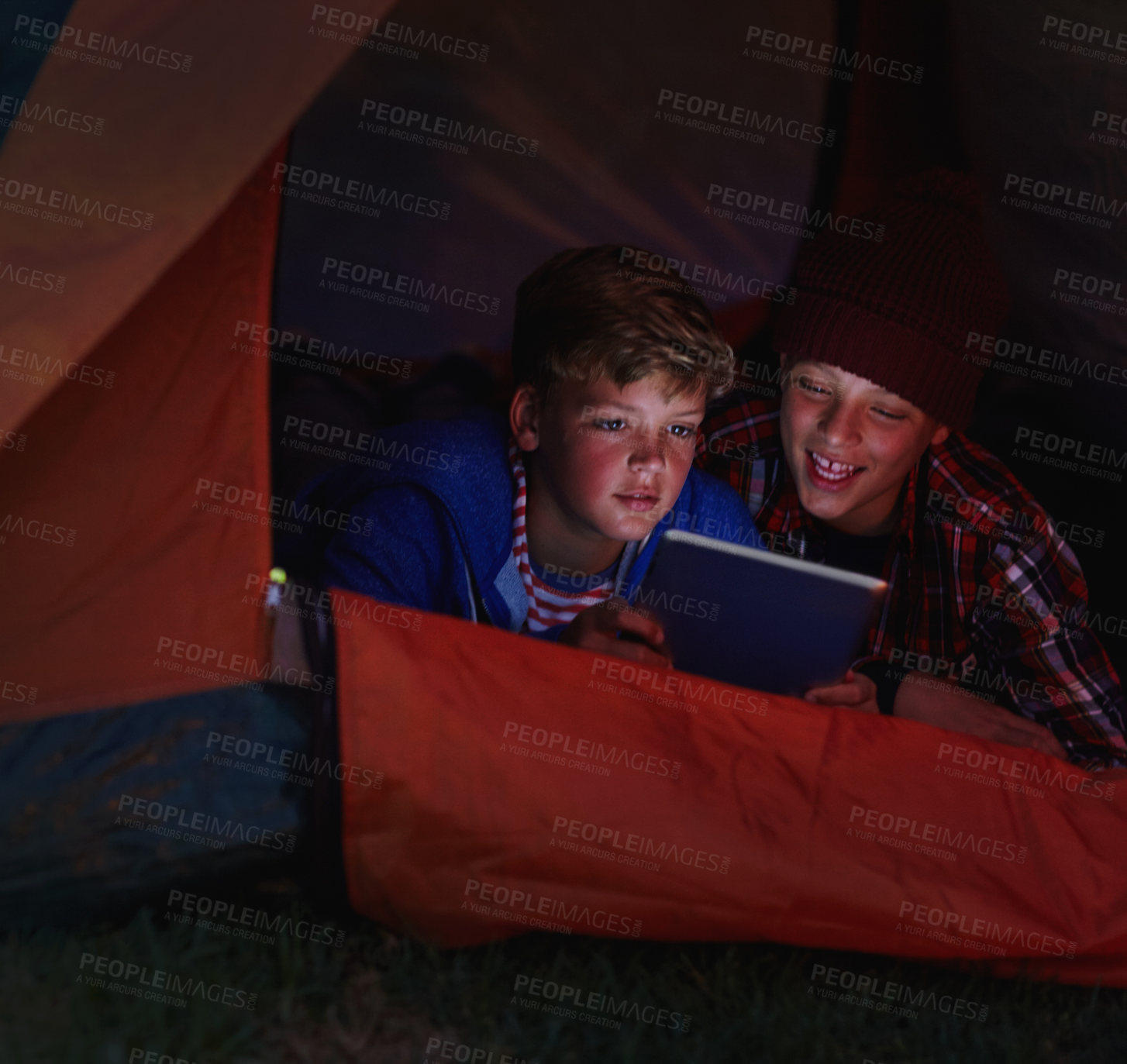 Buy stock photo Cropped shot of two young boys sharing a digital tablet while camping