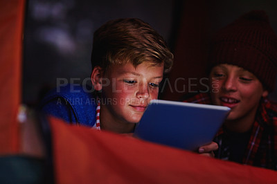 Buy stock photo Cropped shot of two young boys sharing a digital tablet while camping