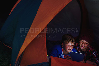 Buy stock photo Cropped shot of two young boys sharing a digital tablet while camping