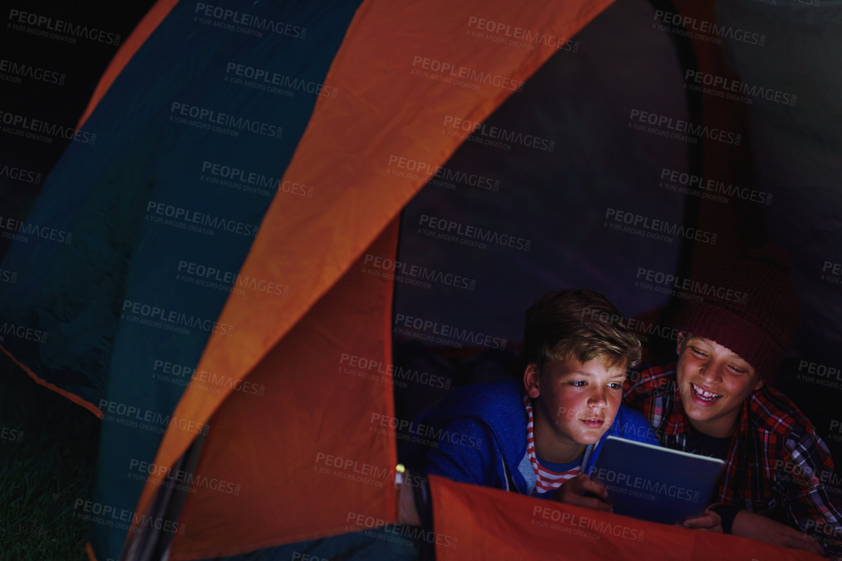 Buy stock photo Cropped shot of two young boys sharing a digital tablet while camping