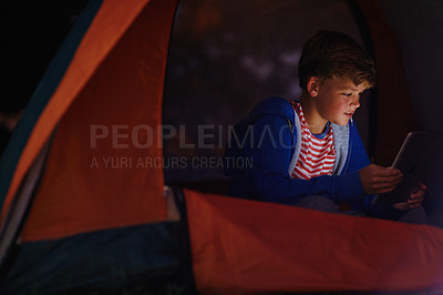 Buy stock photo Cropped shot of a young boy using a digital tablet while camping