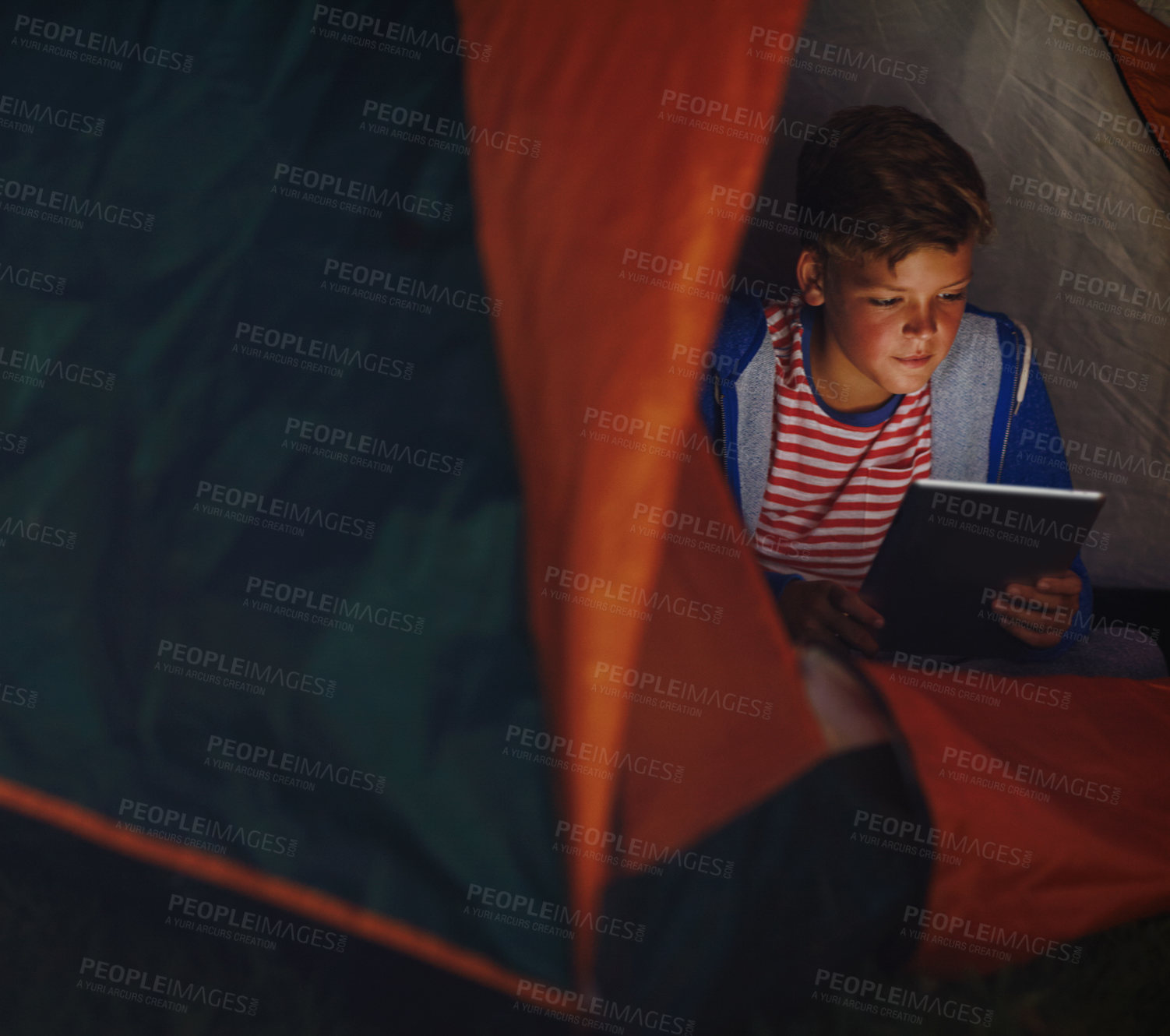 Buy stock photo Cropped shot of a young boy using a digital tablet while camping
