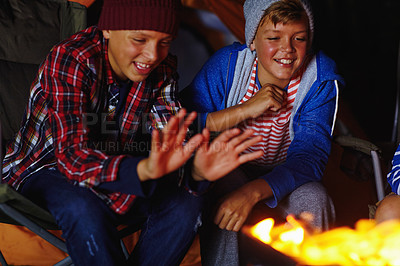 Buy stock photo Cropped shot of two young boys sitting by the campfire