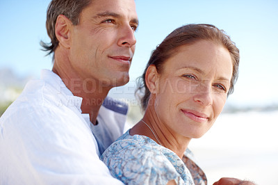 Buy stock photo Portrait of a mature man embracing his happy wife from behind as they stand on the beach