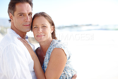 Buy stock photo Portrait of a  mature man embracing his happy wife from behind as they stand on the beach
