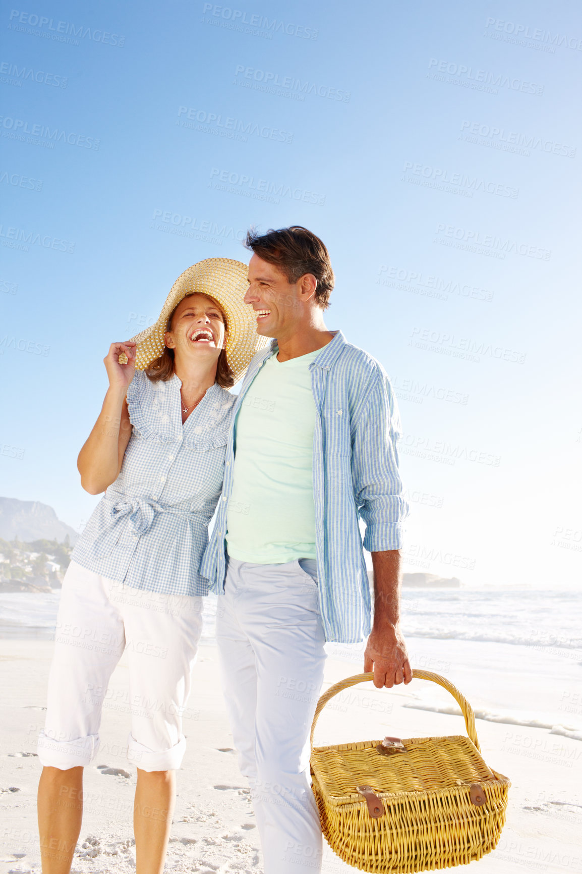 Buy stock photo Laughing, beach and mature couple with picnic, basket and love for summer vacation in Miami. Man, woman and smile with ocean, holiday and bonding for relationship anniversary or weekend date by sea