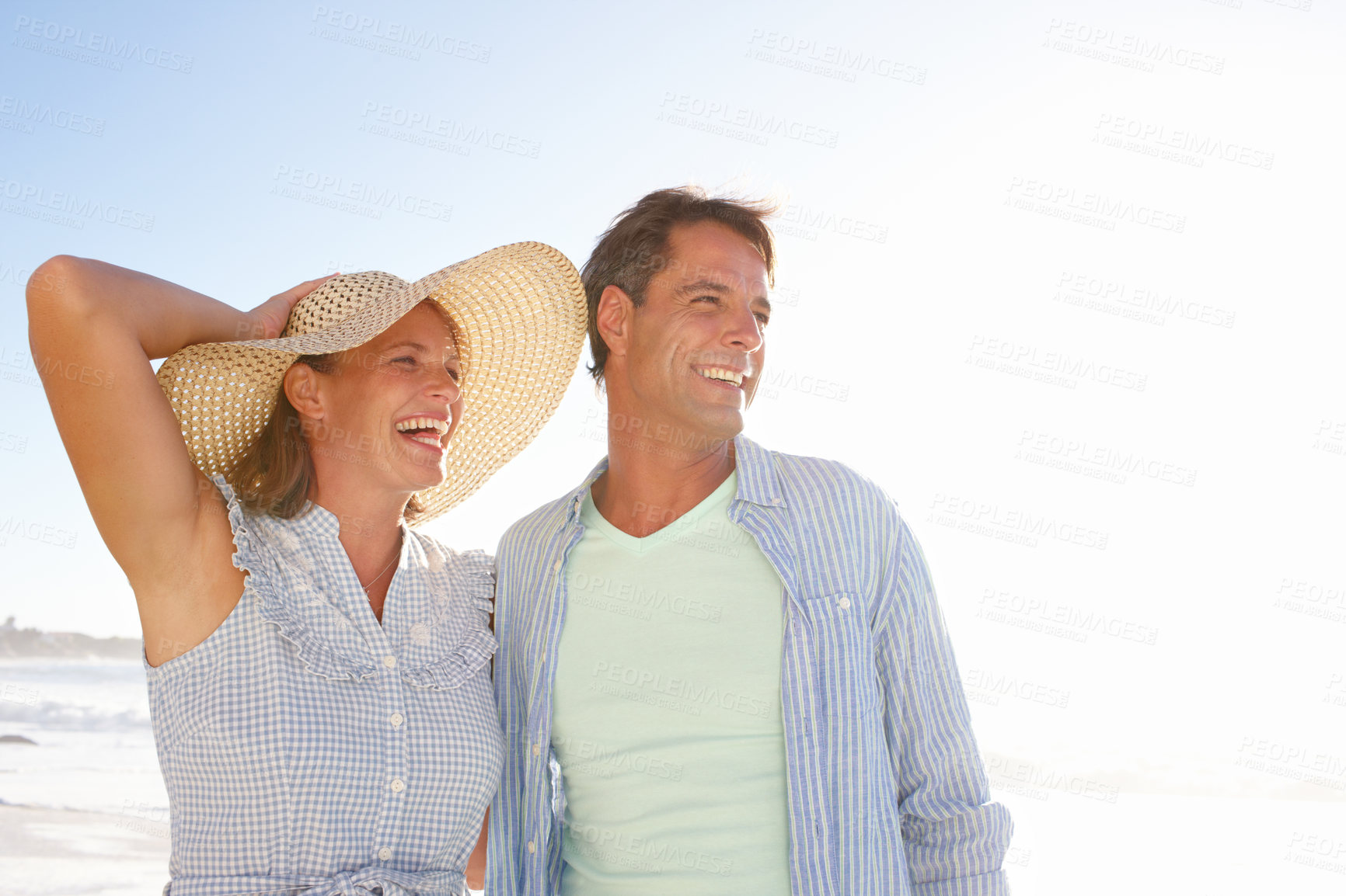 Buy stock photo Happy couple, beach and relax with hat for bonding, love or romance on vacation, anniversary or honeymoon holiday. Man, woman or lovers with smile together for travel, date or ocean trip by sea coast