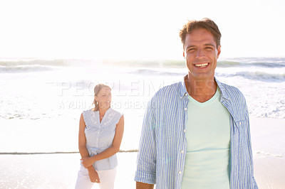 Buy stock photo A handsome mature man enjoying a walk on the beach with his wife