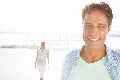 Buy stock photo A handsome mature man enjoying a walk on the beach with his wife