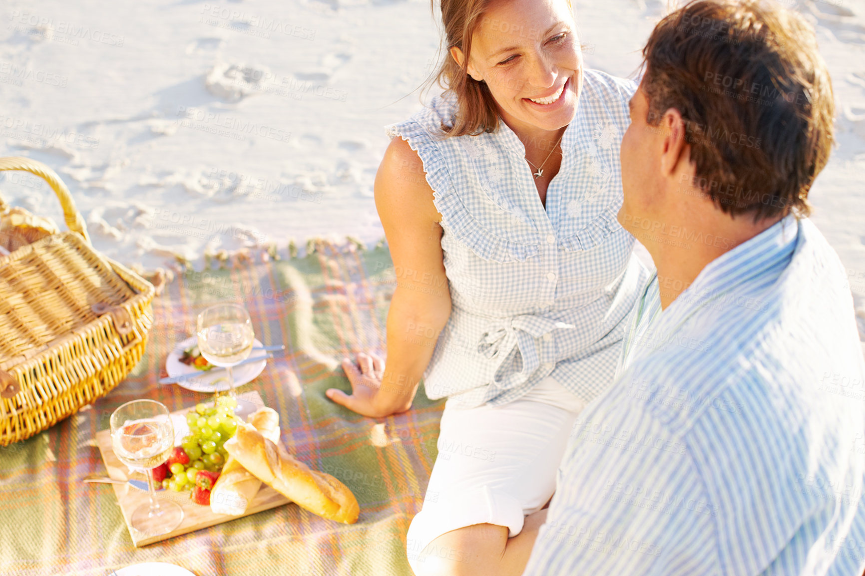 Buy stock photo A devoted couple enjoying a romantic picnic on the beach together