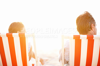 Buy stock photo A mature couple enjoying a beautiful sunset in deckchairs on the beach