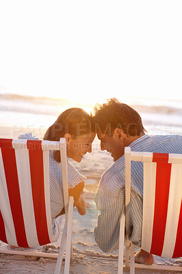 Buy stock photo An affectionate couple sitting on the beach during sunset