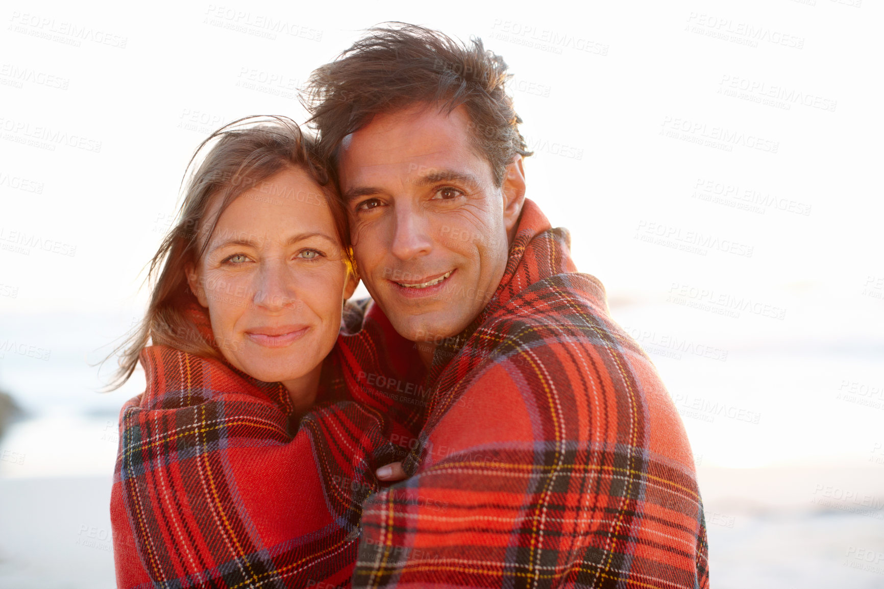Buy stock photo Hug, blanket or couple at ocean for portrait or love on vacation, anniversary or honeymoon holiday. Care, cold or people with smile on date at sea together for travel, bonding or beach trip in Spain