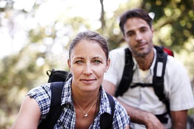 Buy stock photo Beautiful young hiker looking at the camera with her boyfriend sitting in the background