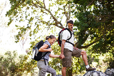 Buy stock photo Male hiker holding his girlfriend's hand while they climb onto a rock - copyspace