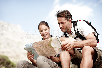 Buy stock photo Two hikers consulting their map while sitting on a mountain top