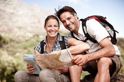 Buy stock photo Two hikers consulting their map while sitting on a mountain top