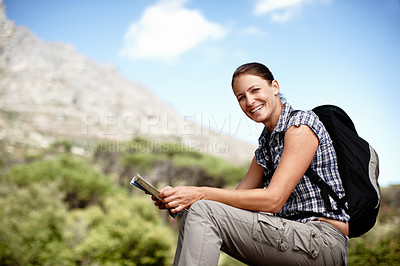 Buy stock photo Young female hiker consulting her map while sitting on a mountain top