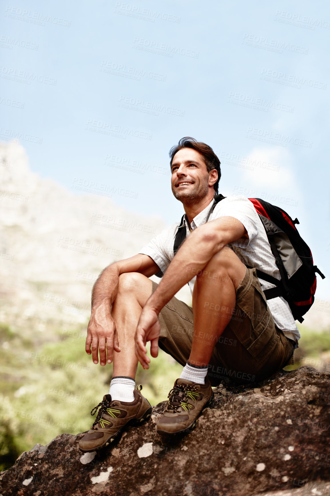 Buy stock photo Relax, hiking and man on mountain with thinking, smile and fitness on holiday adventure in low angle. Break, inspiration and happy hiker on hill with backpack, rest and outdoor vacation in nature.