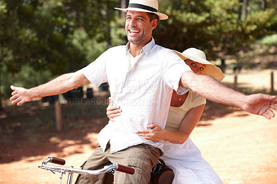 Buy stock photo Playful couple having fun while riding on retro bicycle together