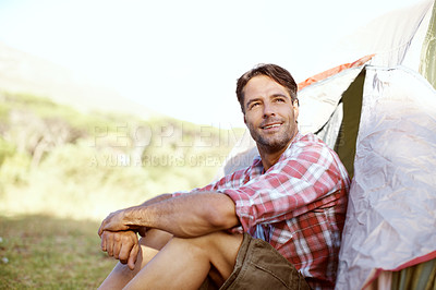 Buy stock photo A handsome young man sitting at the entrance to his tent