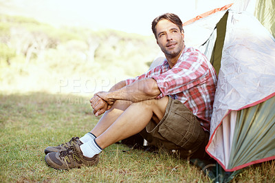 Buy stock photo A handsome young man sitting just outside his tent