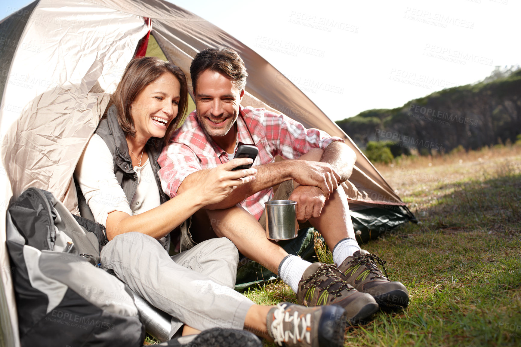 Buy stock photo Couple, nature and camping with phone by tent for social media meme, funny video and connection in woods. People, happy and browsing smartphone on getaway with comic joke and internet fun on campsite