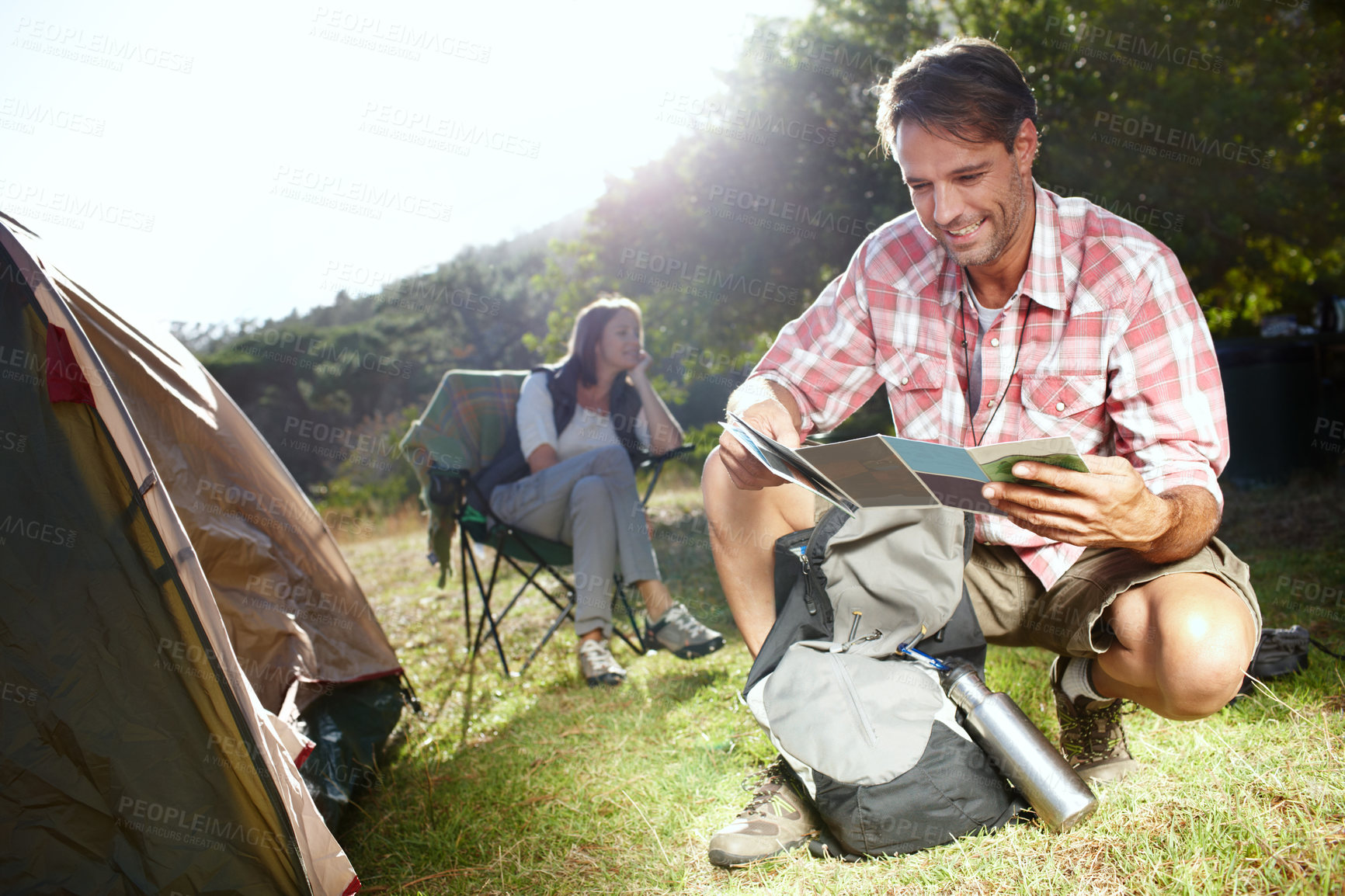 Buy stock photo Man, camping and reading map by tent on adventure with woman, partner and smile on grass in nature. Person, chart and navigation with route, trekking and happy with direction for vacation in Germany