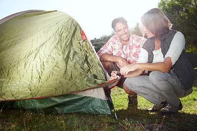 Buy stock photo A young couple setting up their tent