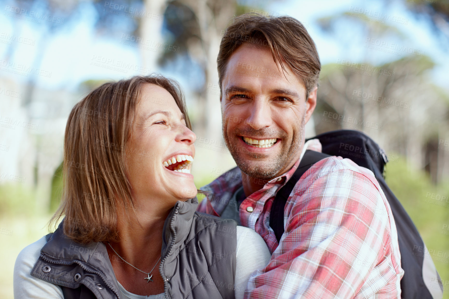 Buy stock photo Hug, laughing or couple in nature for hiking, outdoor adventure or travel journey in woods. Love, funny joke or happy people in forest together for holiday vacation, trip or trekking to explore park