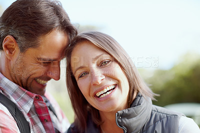 Buy stock photo A young couple leaning against each other and laughing while hiking
