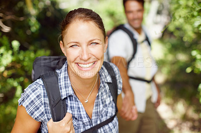 Buy stock photo Portrait of a young woman wearing a backpack with her husband in the background