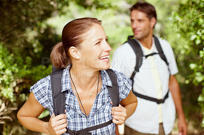 Buy stock photo A young couple walking in a park with backpacks