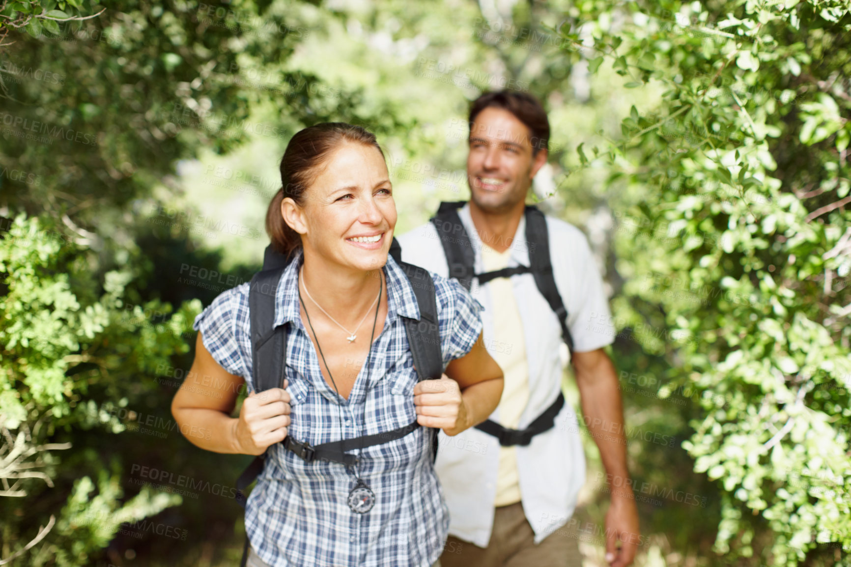 Buy stock photo Couple, walking and smile in nature for hiking, fitness and adventure with bonding, love and support. Man, woman and  forest outdoor for exercise, health or trekking with journey, travel and backpack