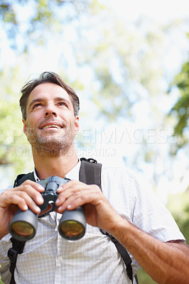 Buy stock photo A young man looking into the distance with his binoculars in his hands