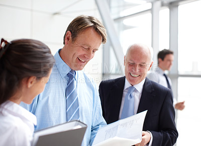 Buy stock photo Smiling businesspeople going through documents together in an informal meeting 