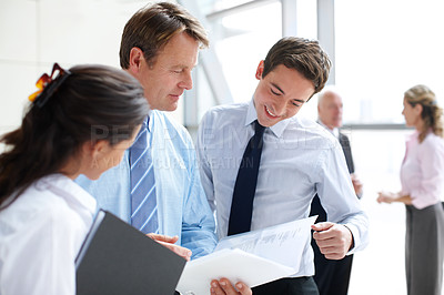 Buy stock photo Business associates going through documents together in an informal meeting 