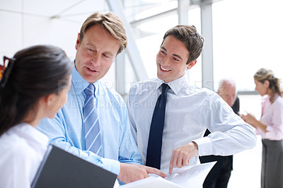 Buy stock photo Business executives going through documents together in an informal meeting 